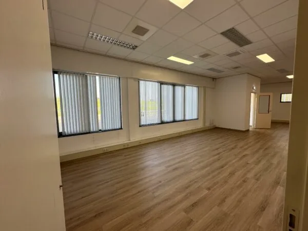 Leeg kantoorpand aan de Van der Hagenstraat met laminaatvloer, systeemplafond en grote ramen met verticale lamellen.